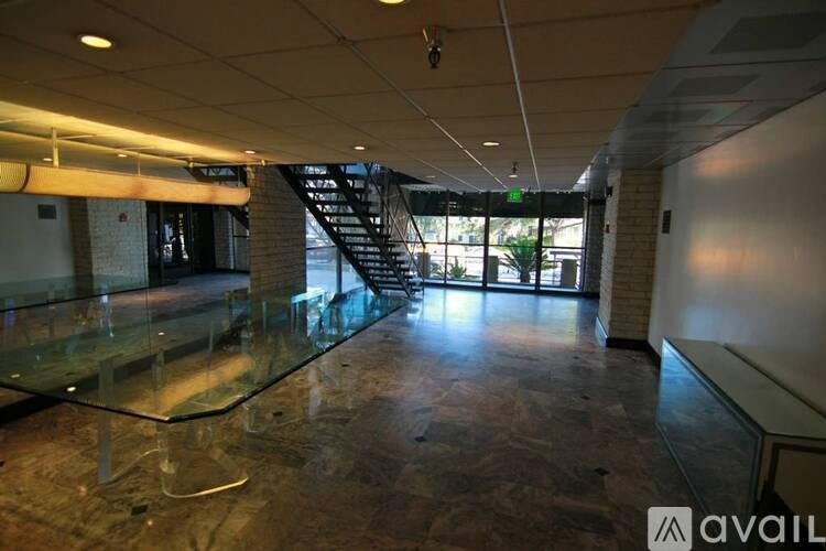 A spacious room with a glass table and a staircase in the background.