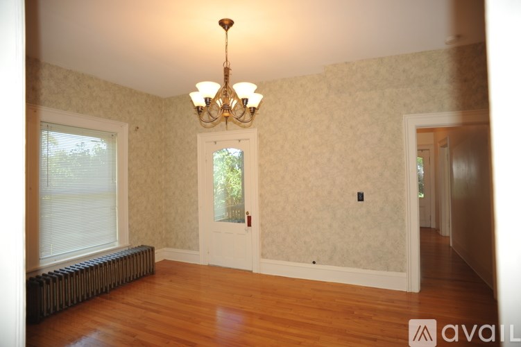 A room with a chandelier and a window with blinds.