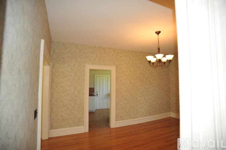 A room with a wooden floor and a chandelier hanging from the ceiling.