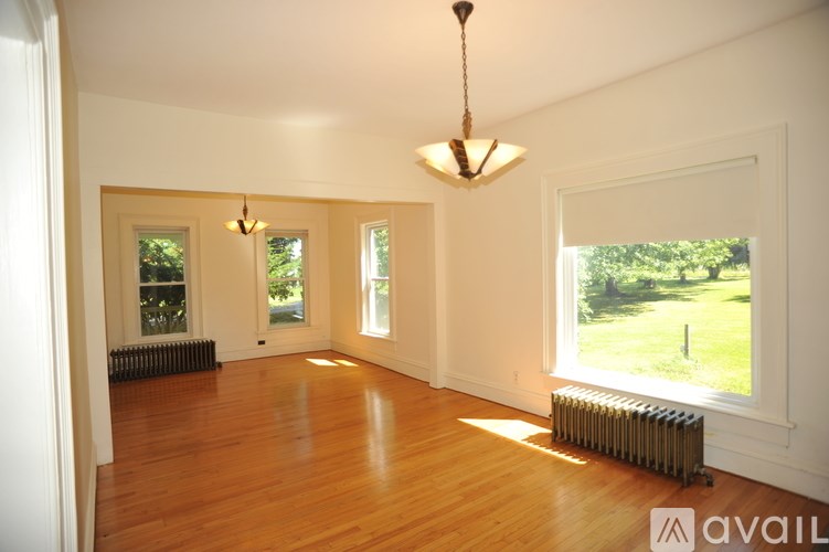 A large empty room with wooden floors and a chandelier hanging from the ceiling.