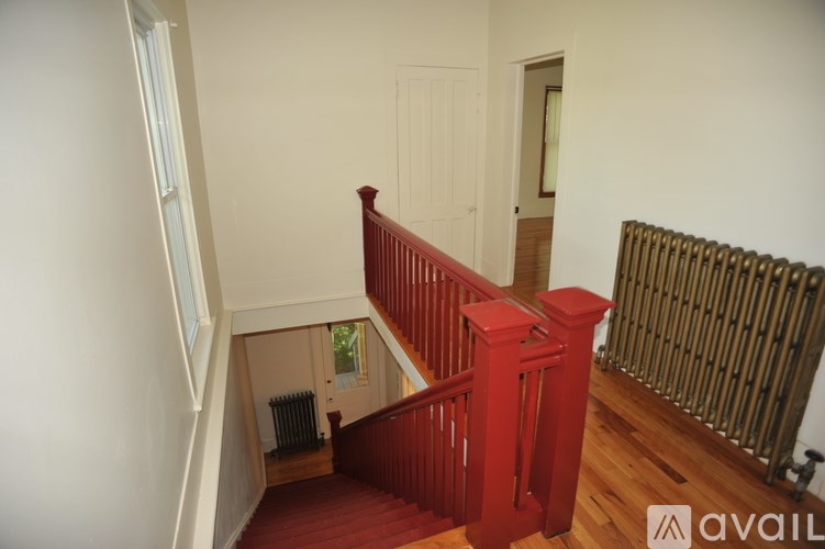 A red staircase with a wooden handrail.