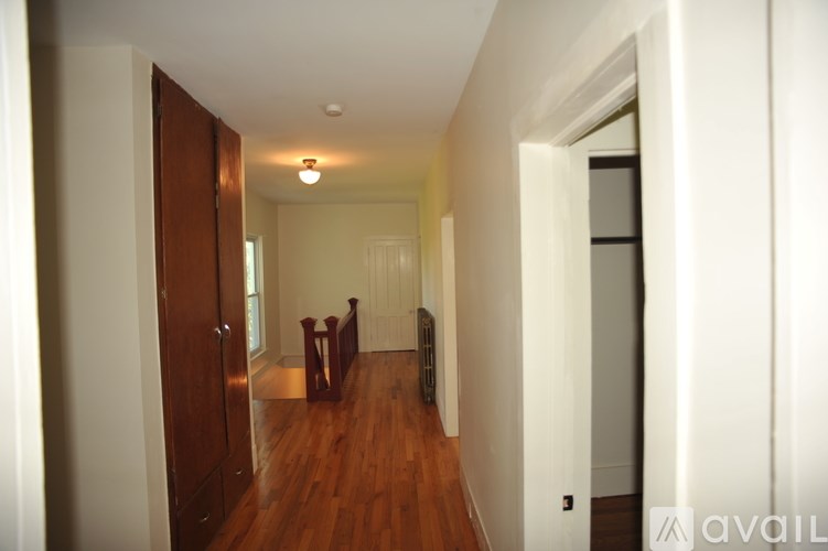 A hallway with a wooden floor and white walls.
