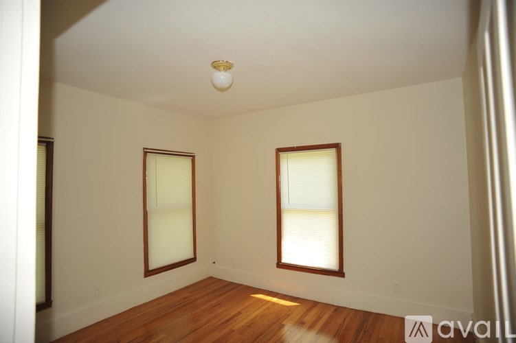 A room with wooden floors and two windows.