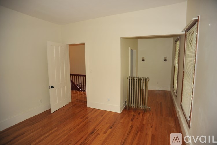 A room with wooden floors and a white wall with a door and a window.