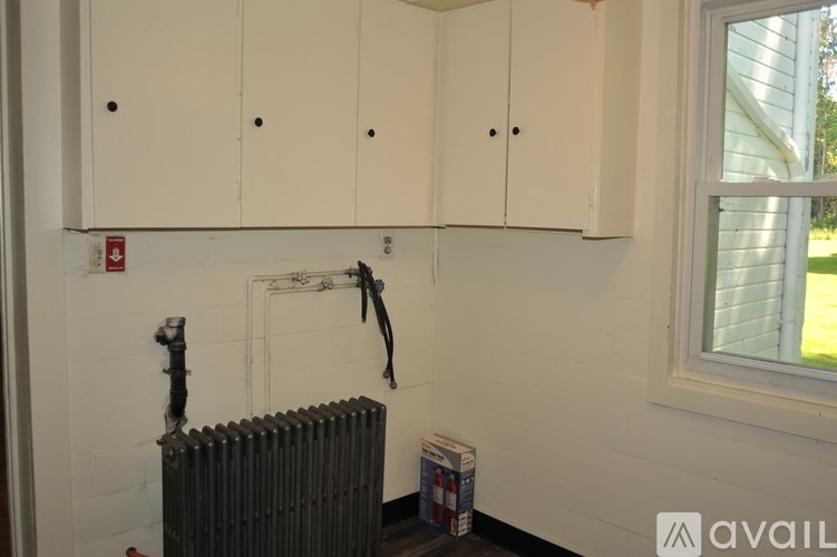A room with white cabinets and a window showing a green lawn outside.