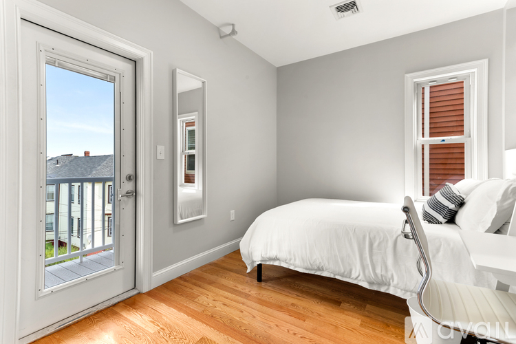 A bedroom with a bed, chair, and a window with blinds.