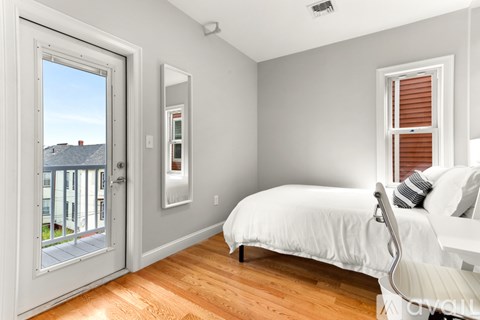 A bedroom with a bed, chair, and a window with blinds.