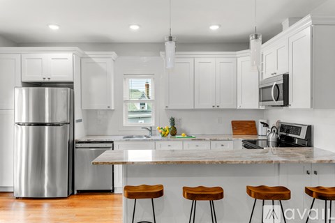 A modern kitchen with white cabinets and a marble countertop.