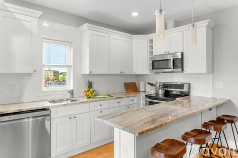A kitchen with white cabinets and a wooden island.