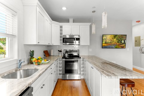 A kitchen with white cabinets and a marble countertop.