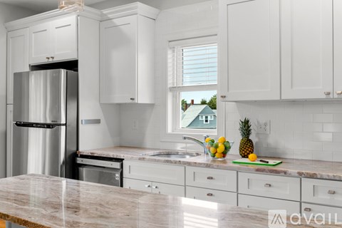 A kitchen with white cabinets and a marble countertop.