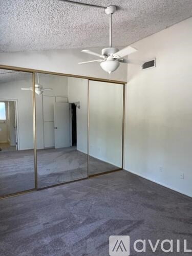 A room with a ceiling fan and a glass door.