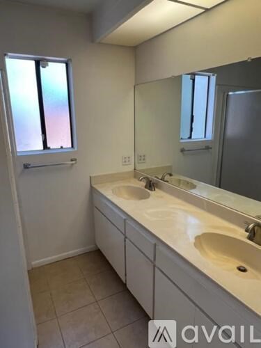 A bathroom with a double sink vanity and a window.