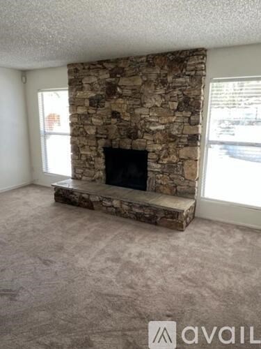 A stone fireplace in a room with a carpeted floor.