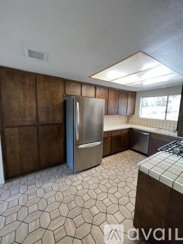 A kitchen with a tile floor and a stainless steel refrigerator.