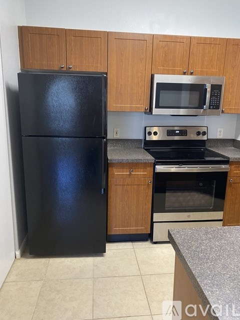 A black fridge and microwave in a kitchen.