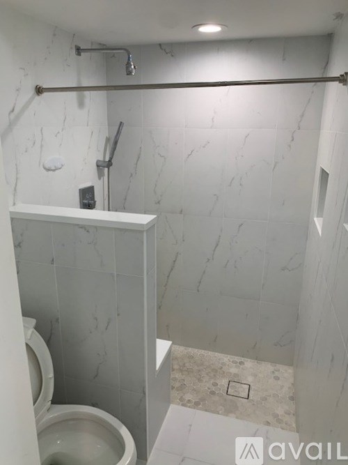 A bathroom with a toilet and a marble wall.
