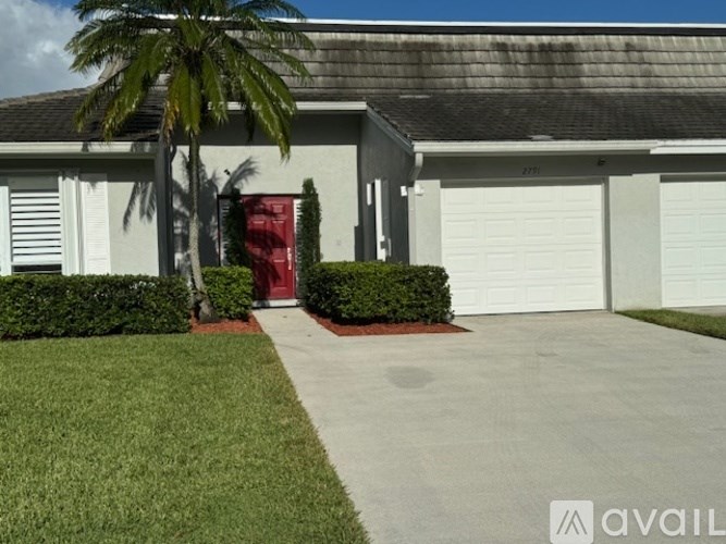 A house with a red door and a palm tree in front.