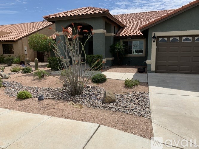 A house with a red tile roof and a garden in front.