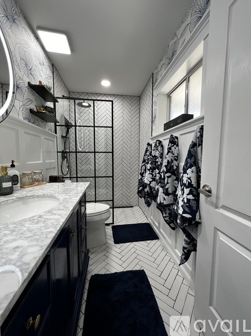 A bathroom with a white sink and a black and white shower.