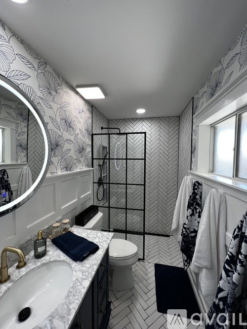 A bathroom with a marble countertop and a patterned wallpaper.