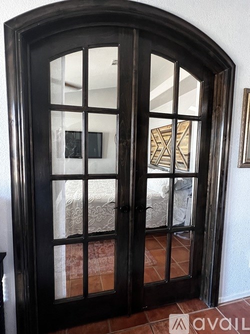 A black door with a glass window and a picture frame on the wall.