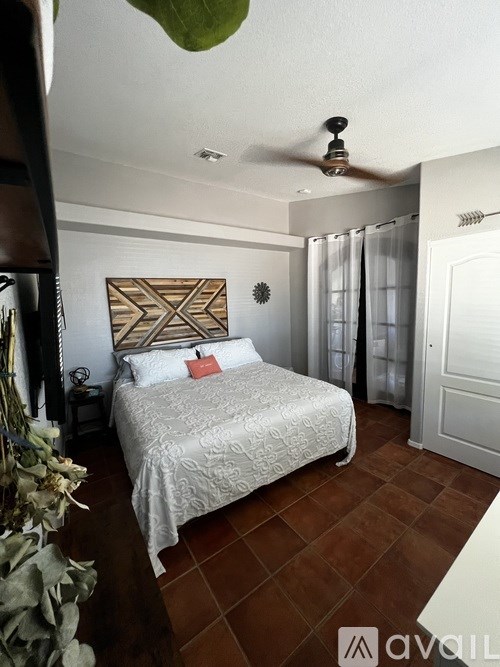 A bedroom with a bed, a ceiling fan, and a wall hanging.
