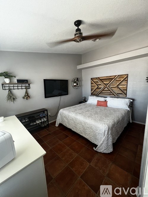 A bedroom with a bed, a television, and a fan.