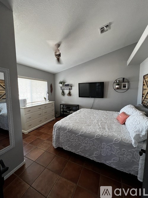 A bedroom with a bed, dresser, and ceiling fan.