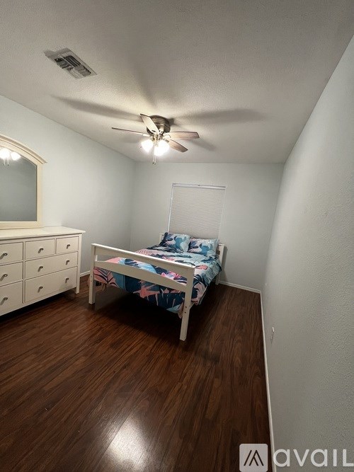A bedroom with a bed, dresser, and ceiling fan.