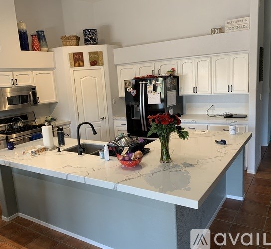 A kitchen with a white countertop and a black fridge.