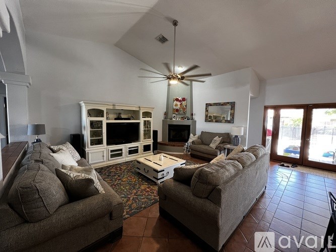 A living room with a grey couch, a white cabinet, and a ceiling fan.