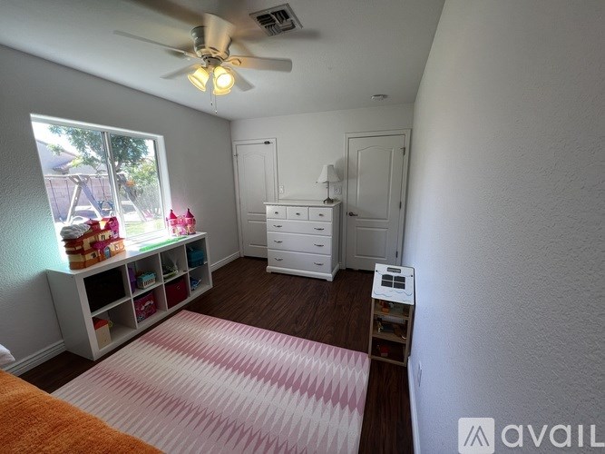 A room with a ceiling fan and a window with a view of a backyard.