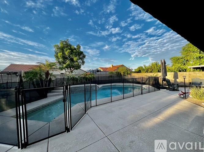 A pool surrounded by a black fence with a house in the background.