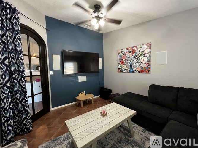 A living room with a black couch, a white coffee table, and a ceiling fan.