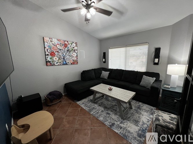 A living room with a black couch and a ceiling fan.