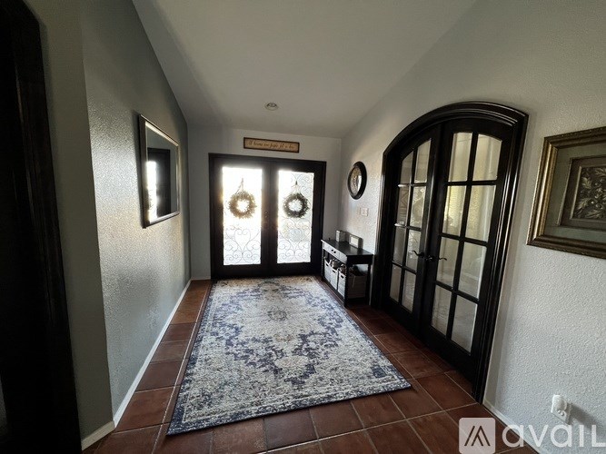 A hallway with a rug and two wreaths on the door.