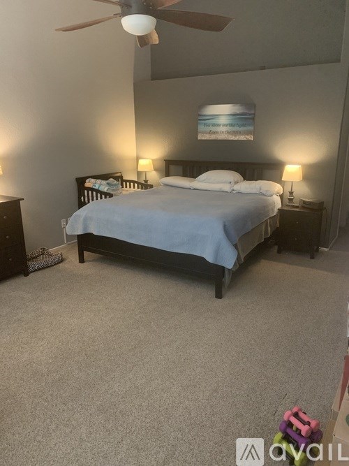 A bedroom with a bed, nightstands, and a ceiling fan.