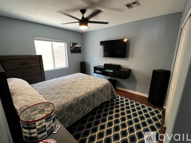 A bedroom with a bed, a television, and a ceiling fan.