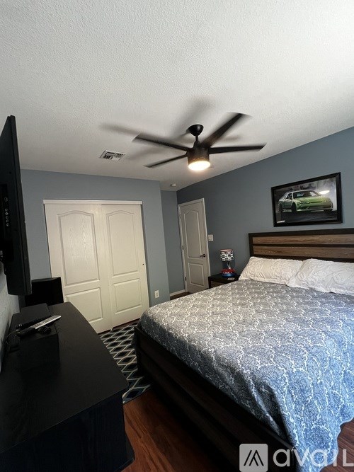 A bedroom with a bed, dresser, and ceiling fan.