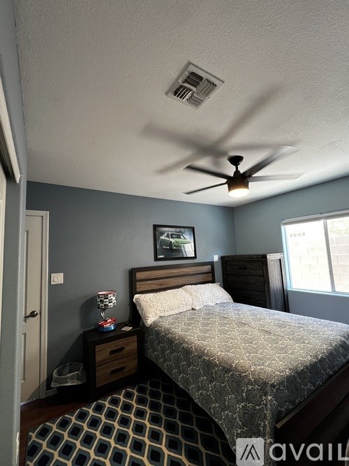 A bedroom with a bed, nightstand, and a ceiling fan.