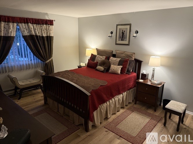 A bedroom with a large bed and a chair.