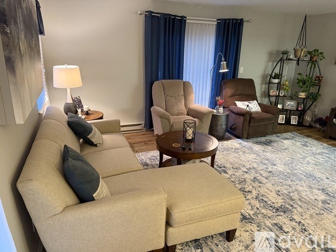 A living room with a beige sofa, a brown armchair, and a wooden coffee table.