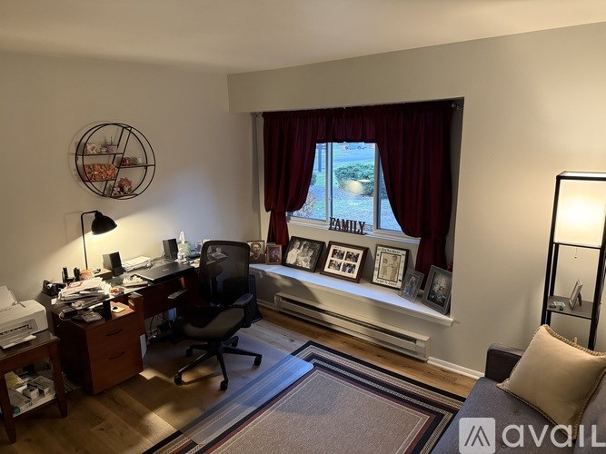 A room with a desk, chair, and a window with a view of a street.