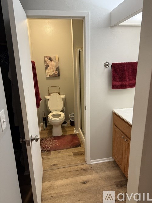A bathroom with a toilet, sink, and a painting on the wall.