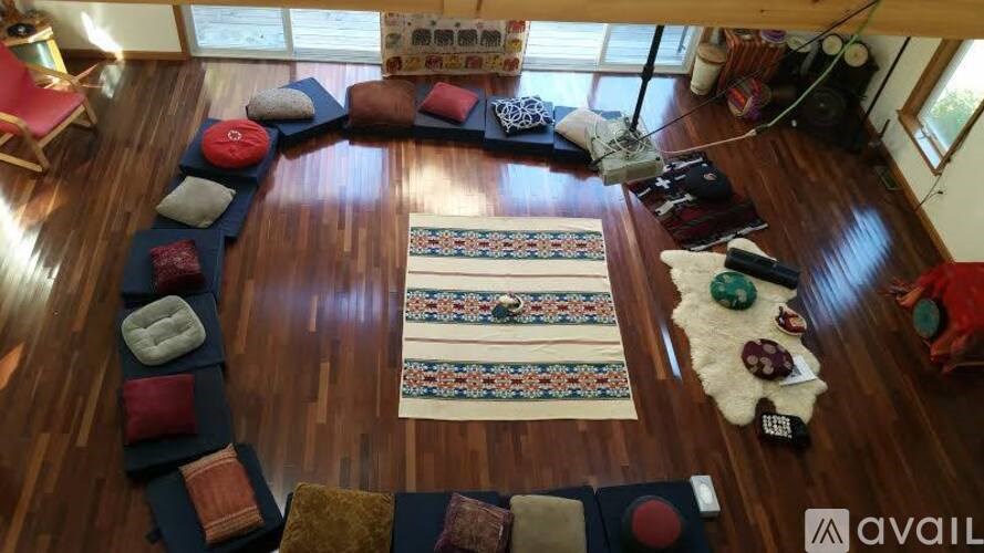 A room with a wooden floor and a rug in the middle.