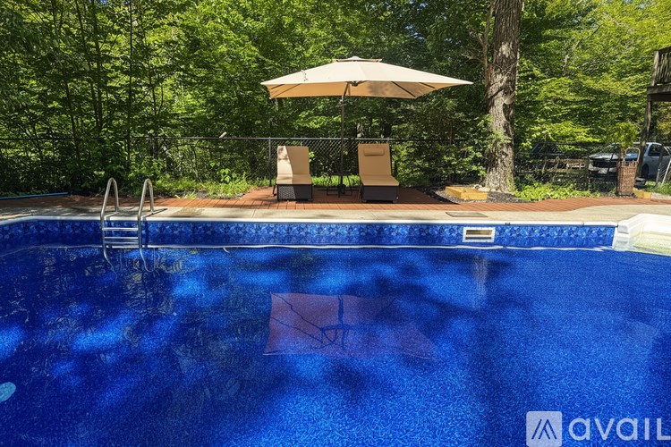 A pool with a sun lounger and umbrella.