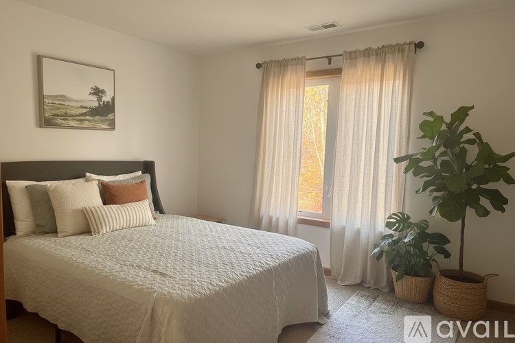 A bedroom with a large bed and a window with curtains.
