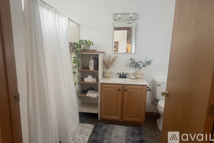 A bathroom with a toilet, sink, and a shower with a white curtain.