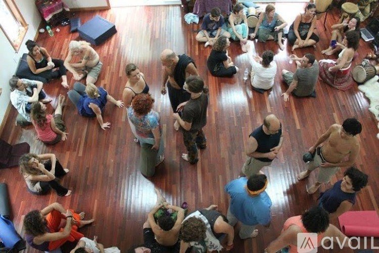 A group of people sitting in a circle on a wooden floor.